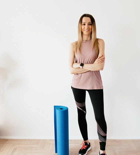 Instructora de pilates de pie junto a su colchoneta — foto referencial